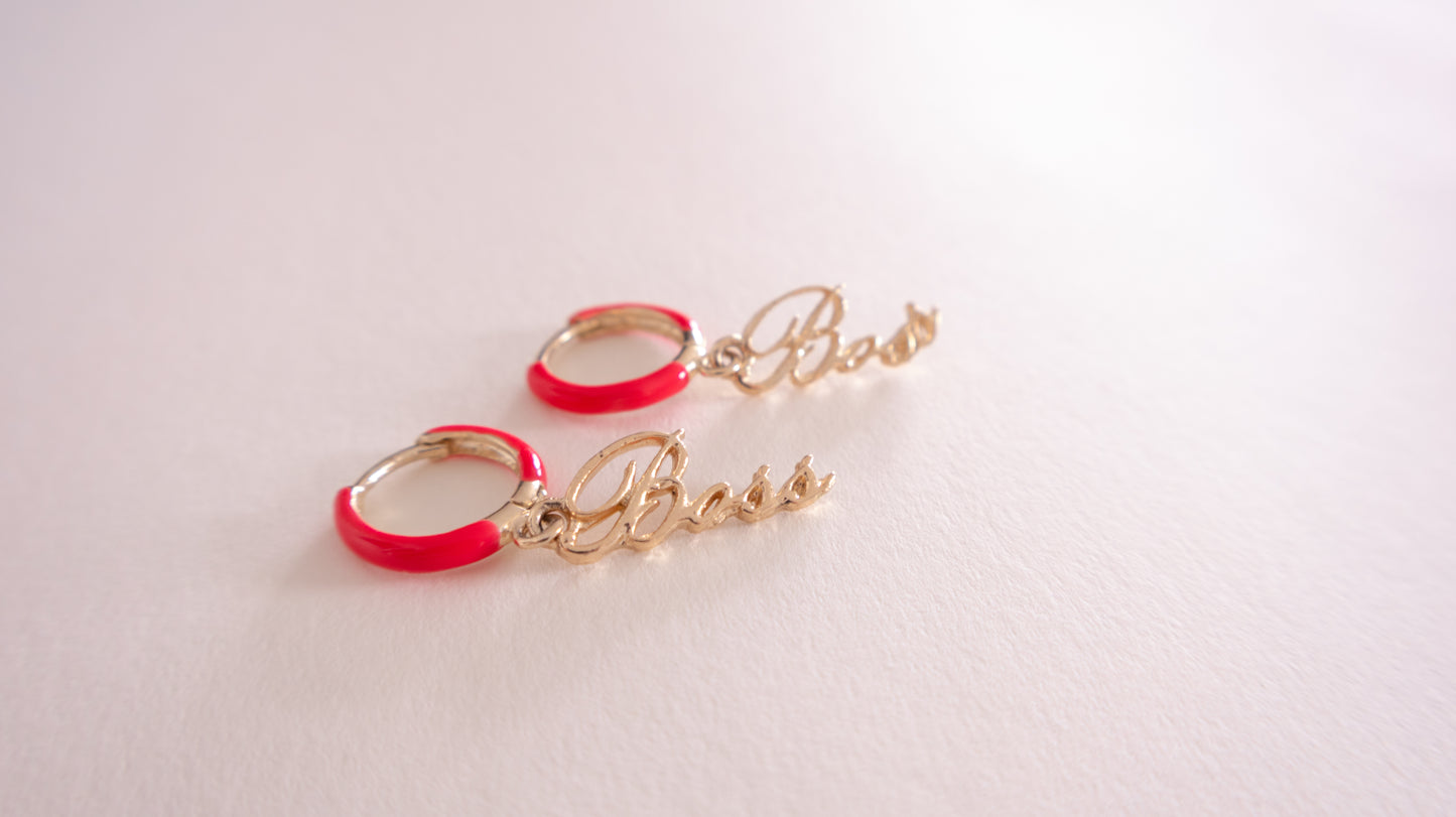 Gold hoop earrings with red accents on a light pink background