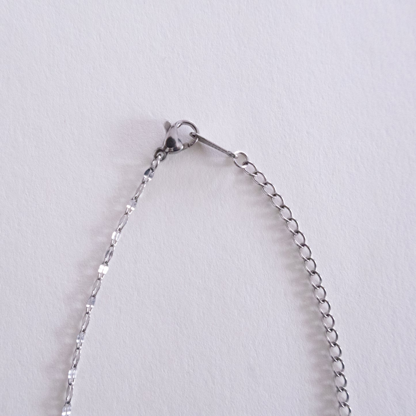 Close-up of a silver chain bracelet on a light gray background
