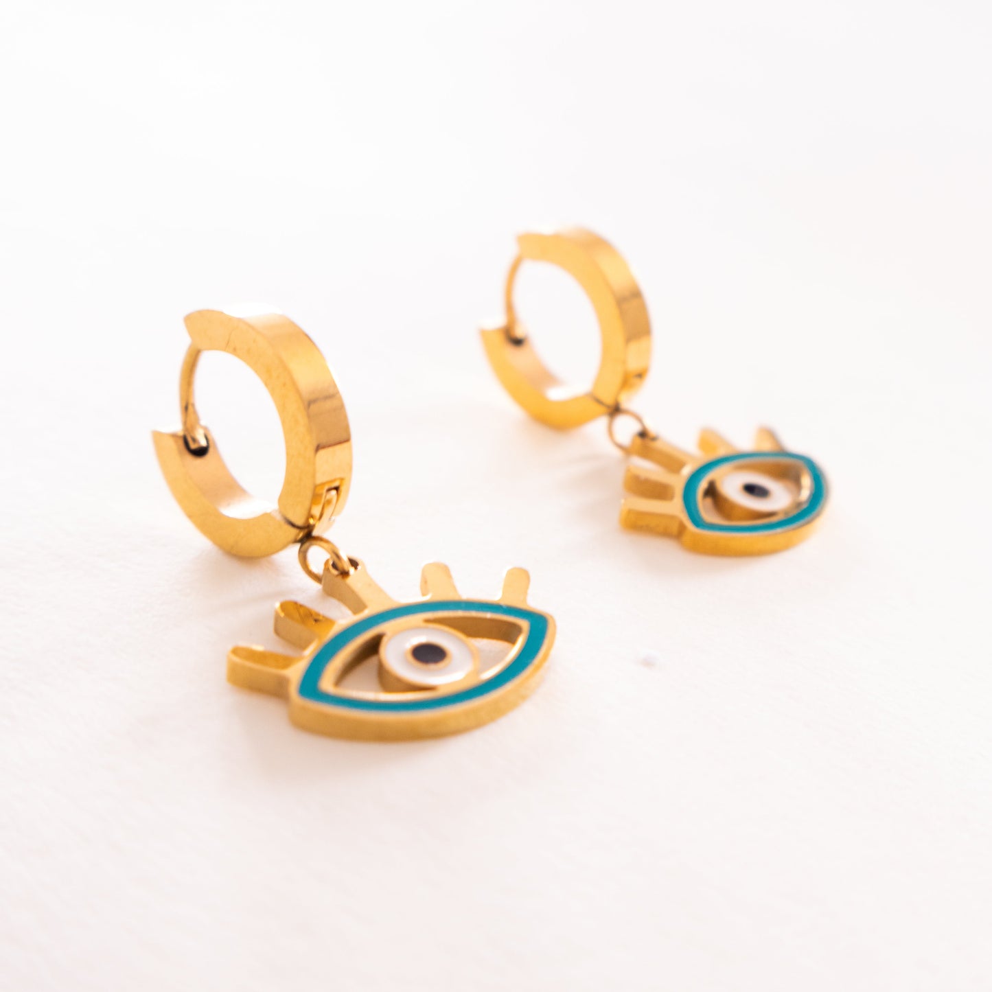 Gold hoop earrings with eye designs on a white background