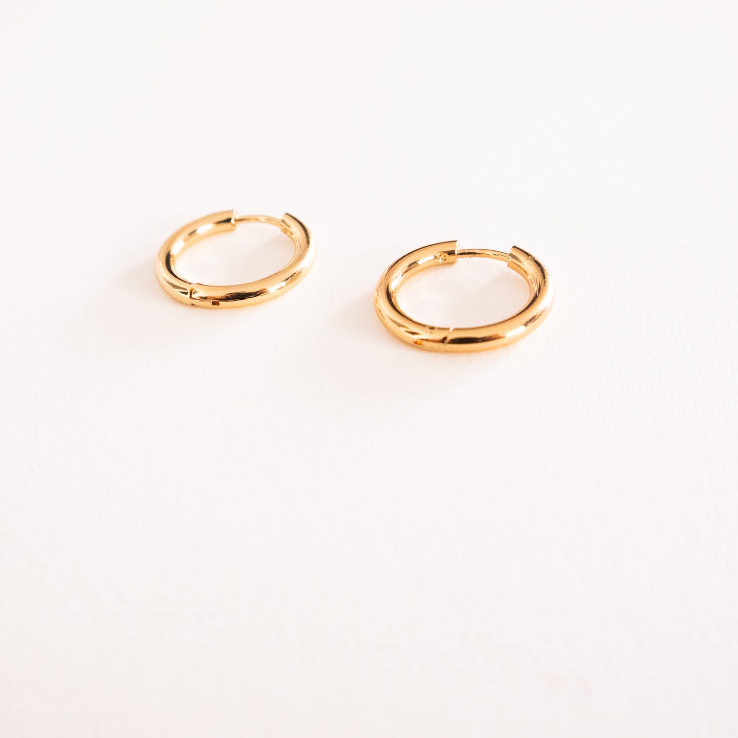 Two gold hoop earrings on a white background