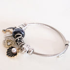 Silver bracelet with various charms on a white background