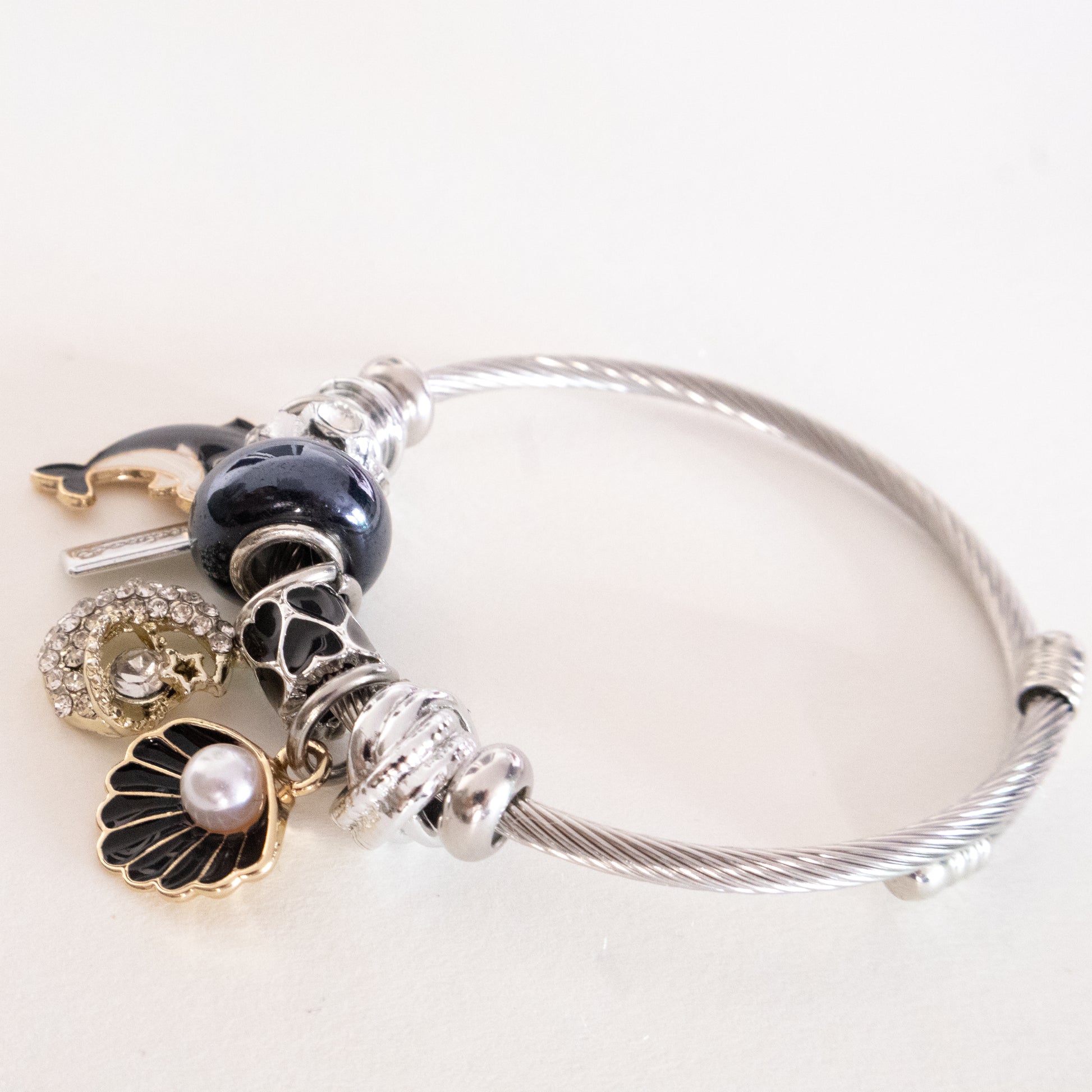 Silver bracelet with various charms on a white background