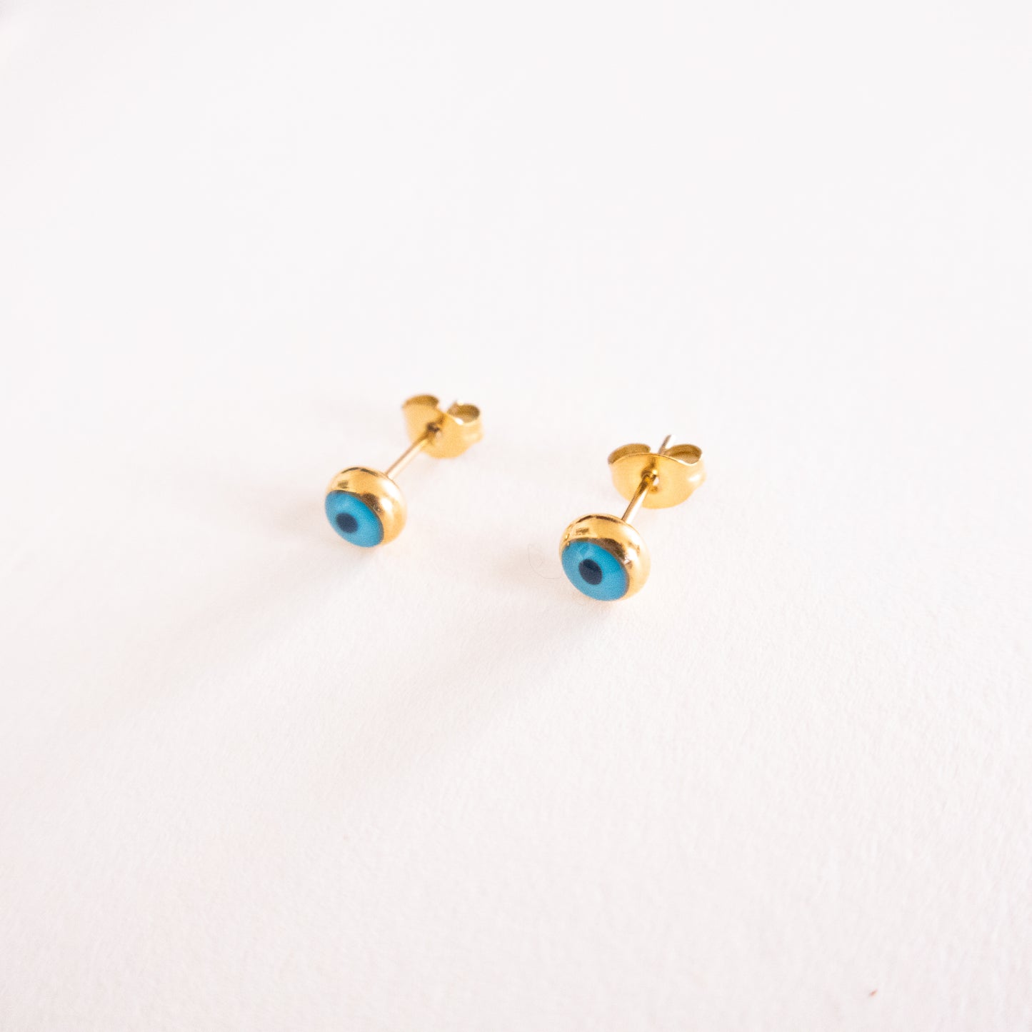 Gold earrings with blue stones on a white background