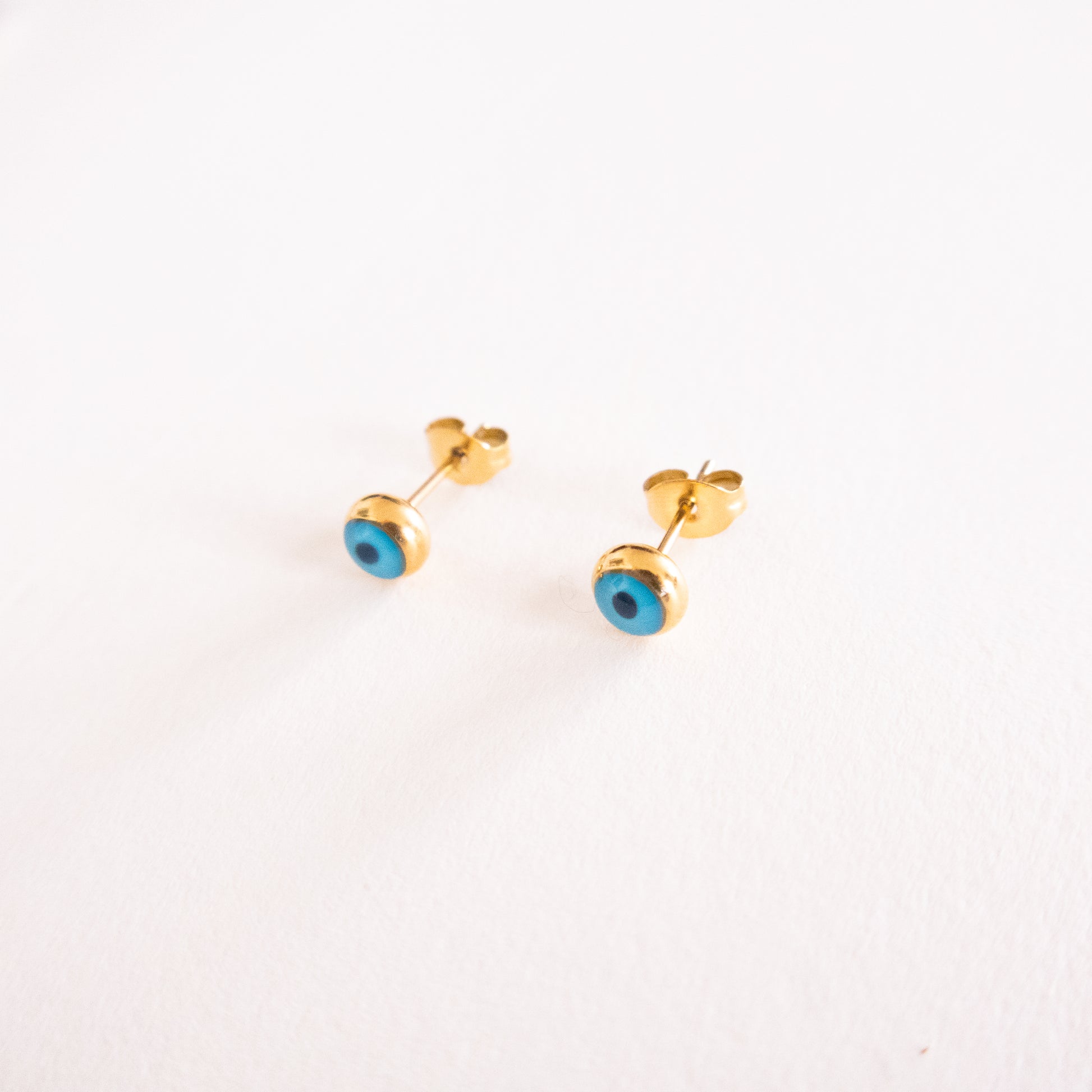 Gold earrings with blue stones on a white background