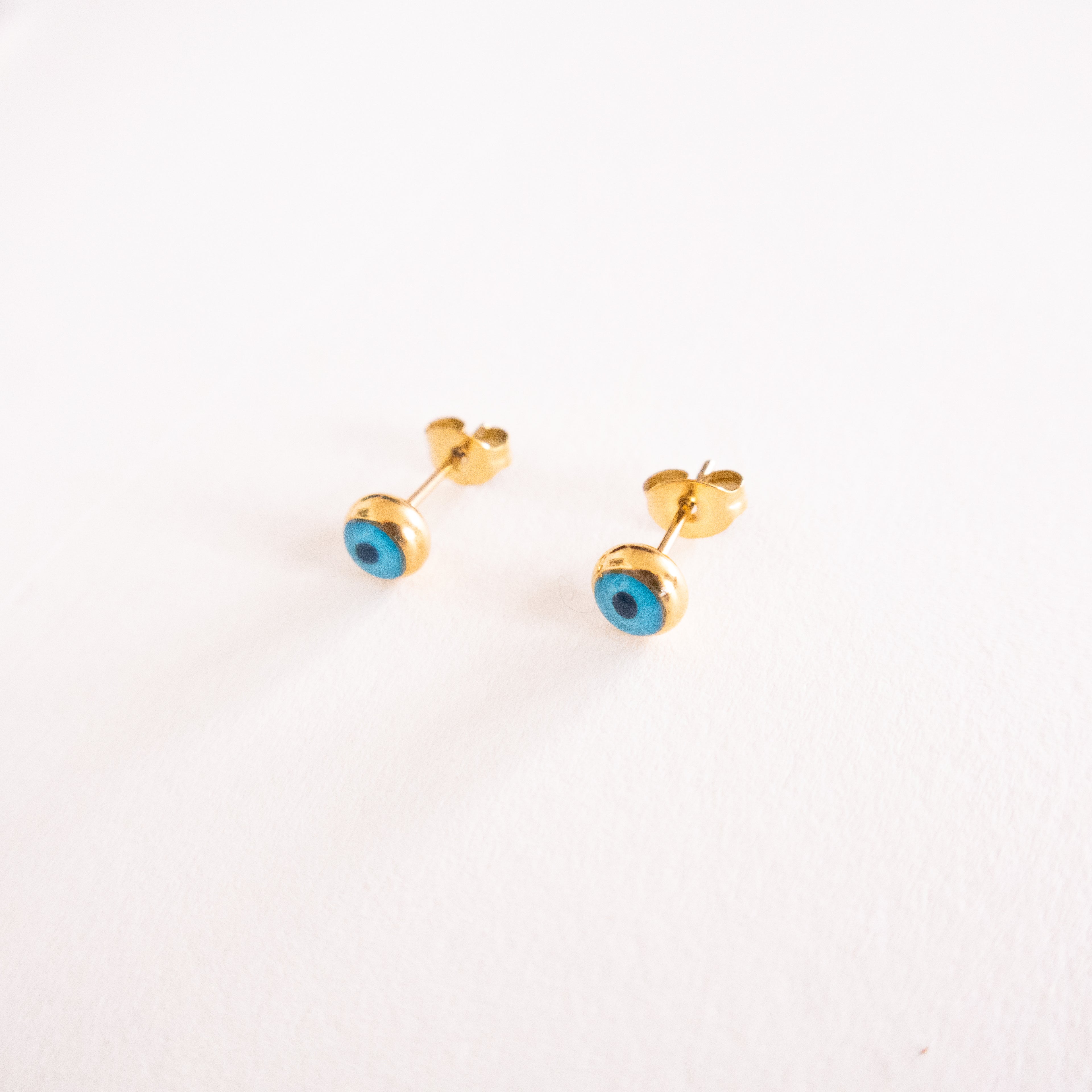 Gold earrings with blue stones on a white background