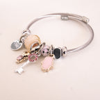 Silver bracelet with various charms on a light pink background