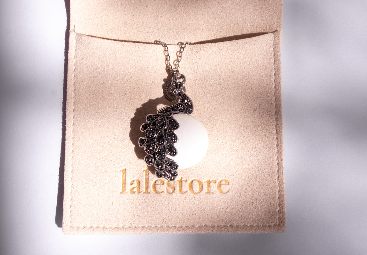A silver-toned necklace with a detailed filigree pendant displayed on a beige jewelry card labeled 'lalestore'.