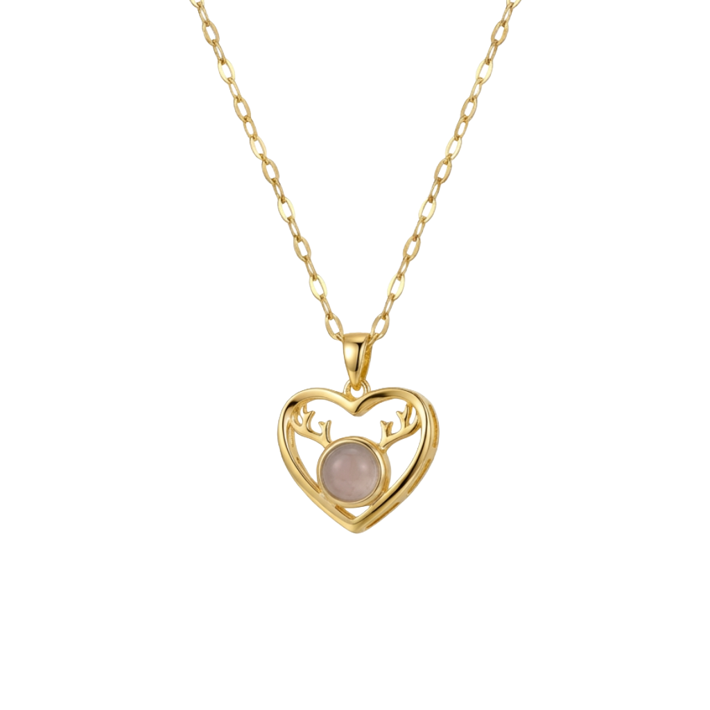 Gold heart-shaped necklace with a pink gemstone on a white background