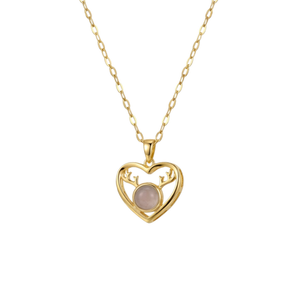 Gold heart-shaped necklace with a pink gemstone on a white background