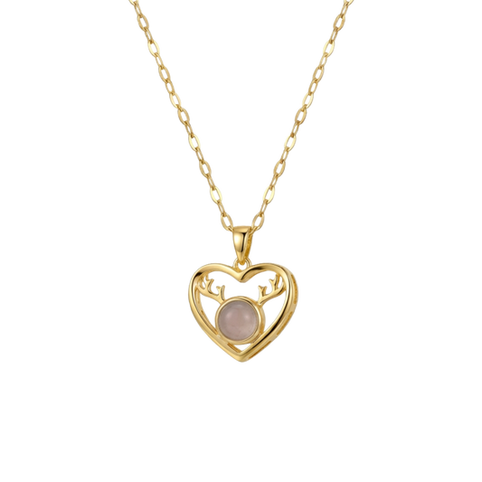 Gold heart-shaped necklace with a pink gemstone on a white background