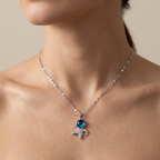 Necklace with a pendant featuring a blue gemstone worn by a person.