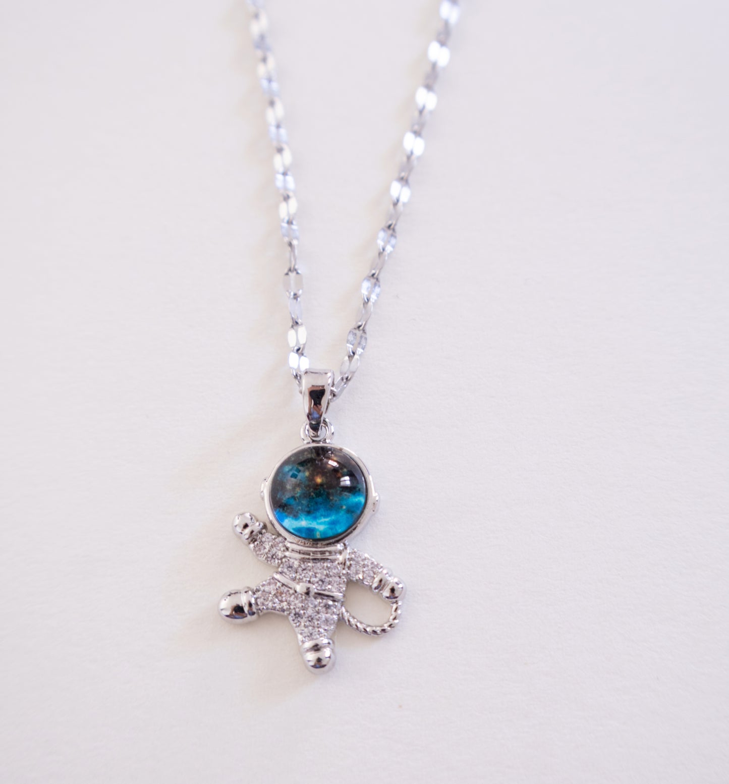 Silver necklace with a blue gemstone pendant on a white background