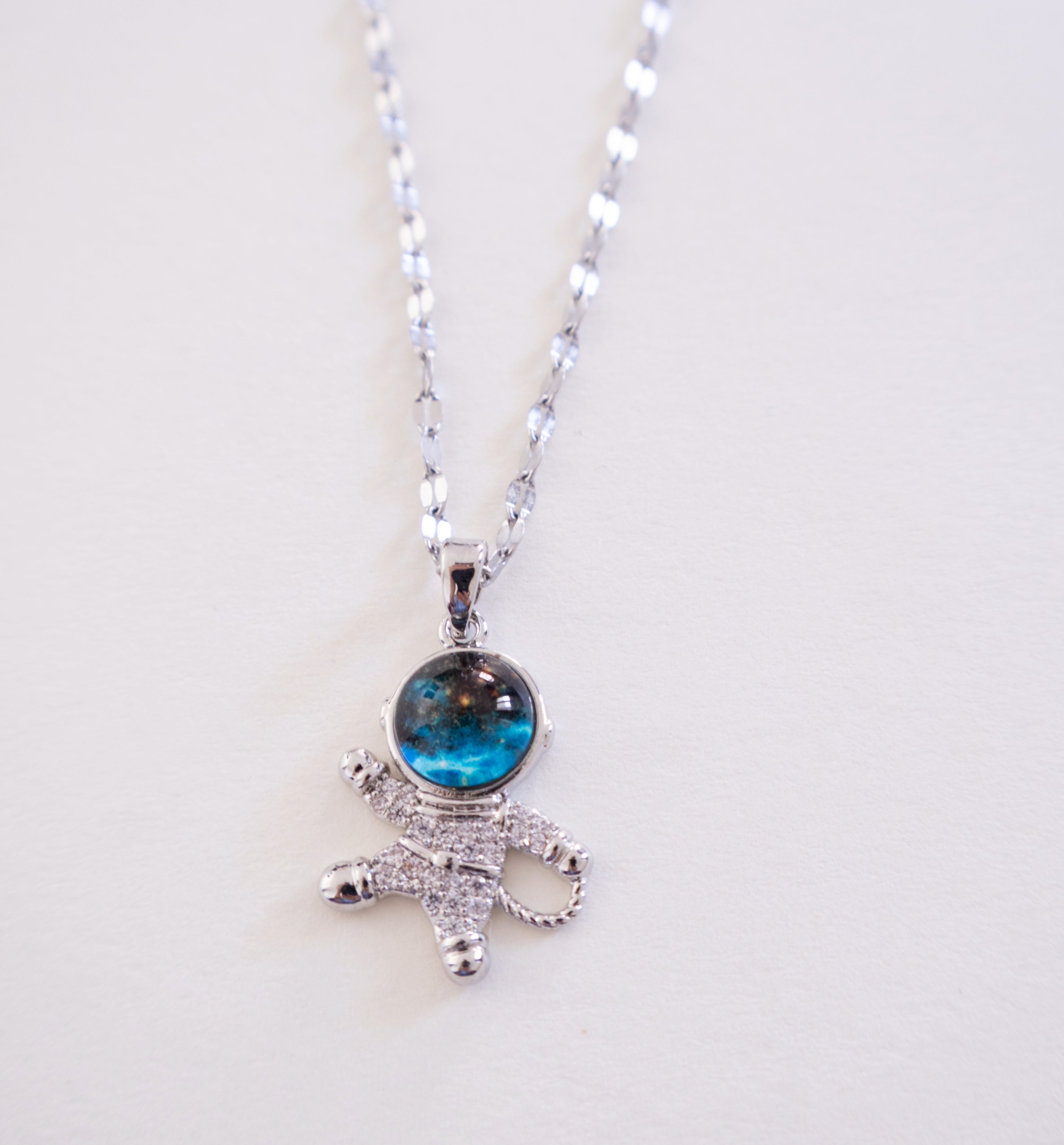 Silver necklace with a blue gemstone pendant on a white background
