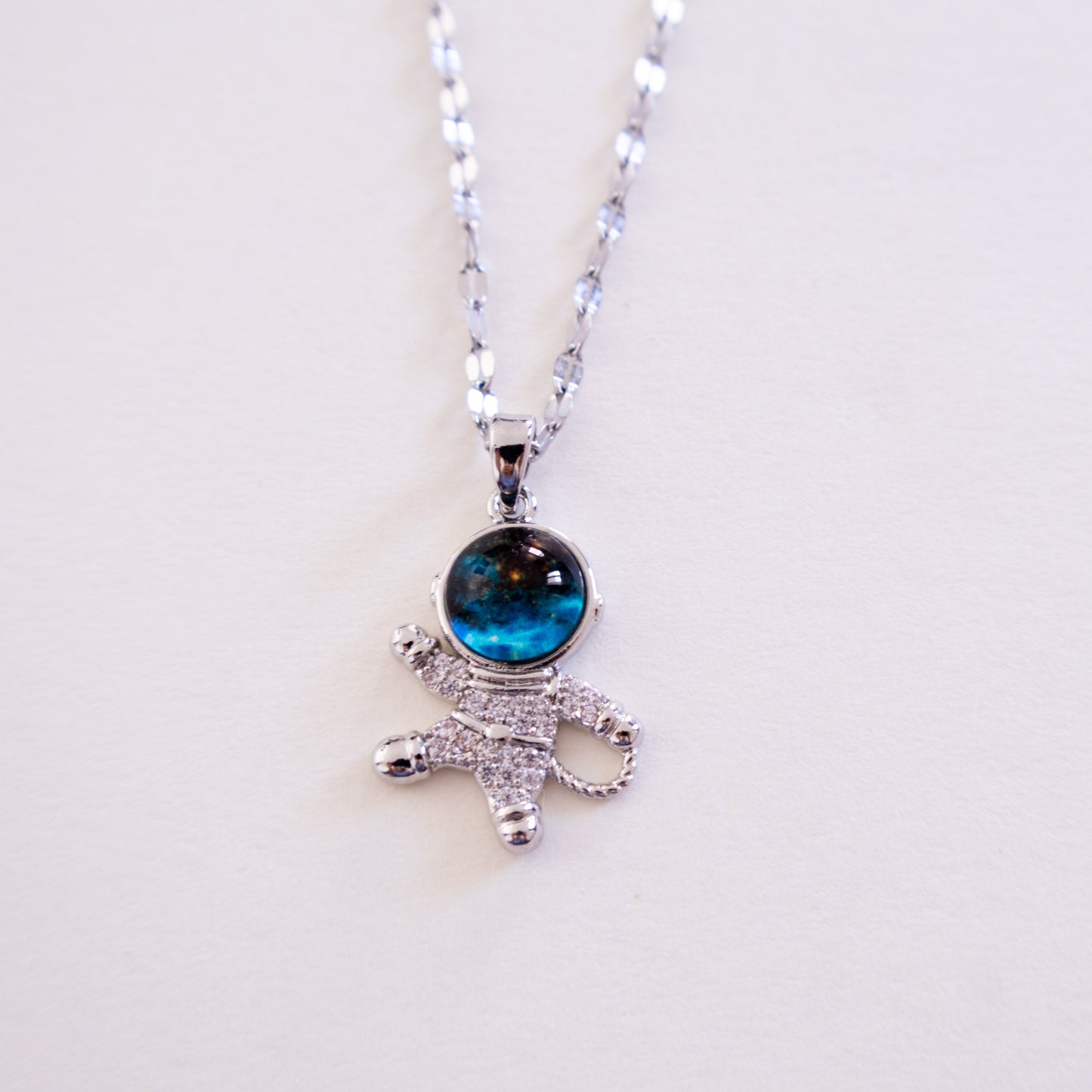 Silver necklace with a blue gemstone pendant on a white background