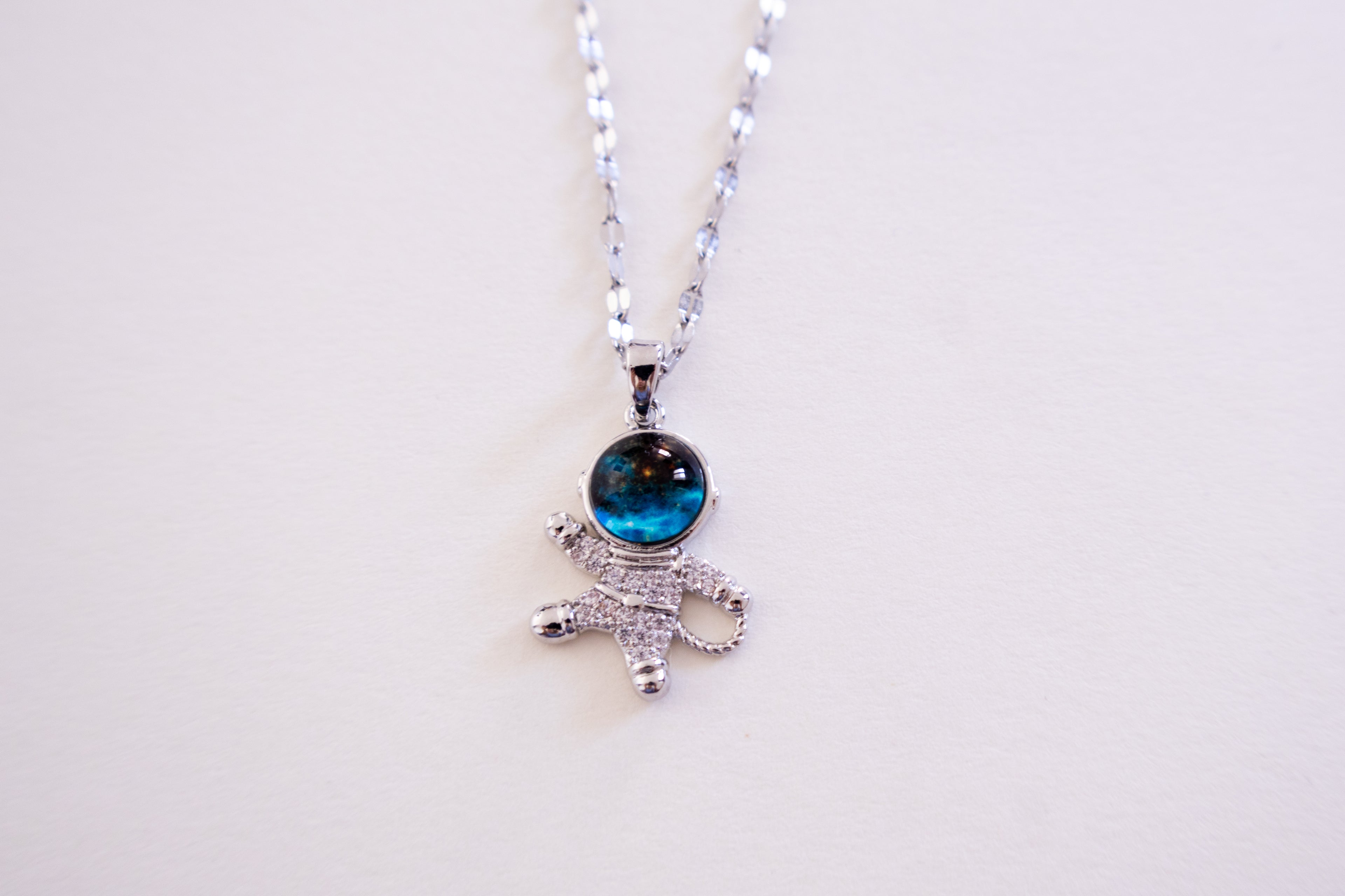 Silver necklace with a blue gemstone pendant on a white background