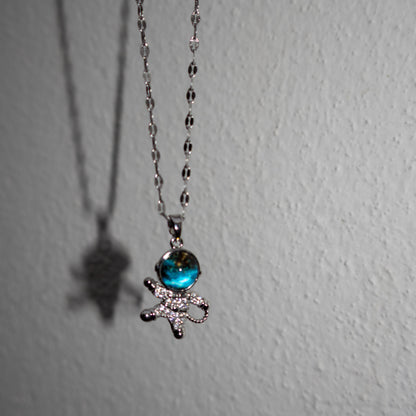 Necklace with a blue gem and bow pendant on a white background