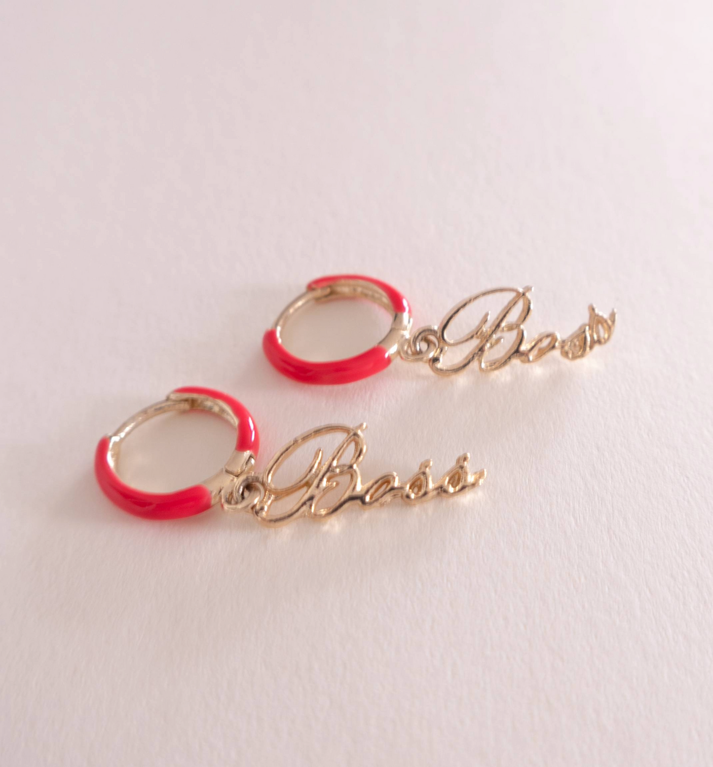 Gold hoop earrings with red accents and 'Boss' inscription on a light gray background