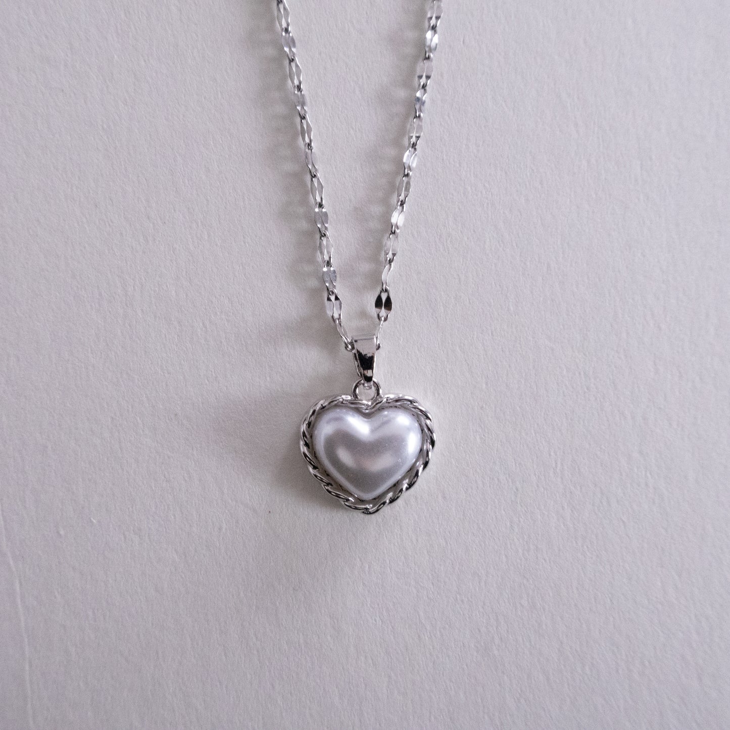 Close-up of a silver chain with black leather straps on a white background