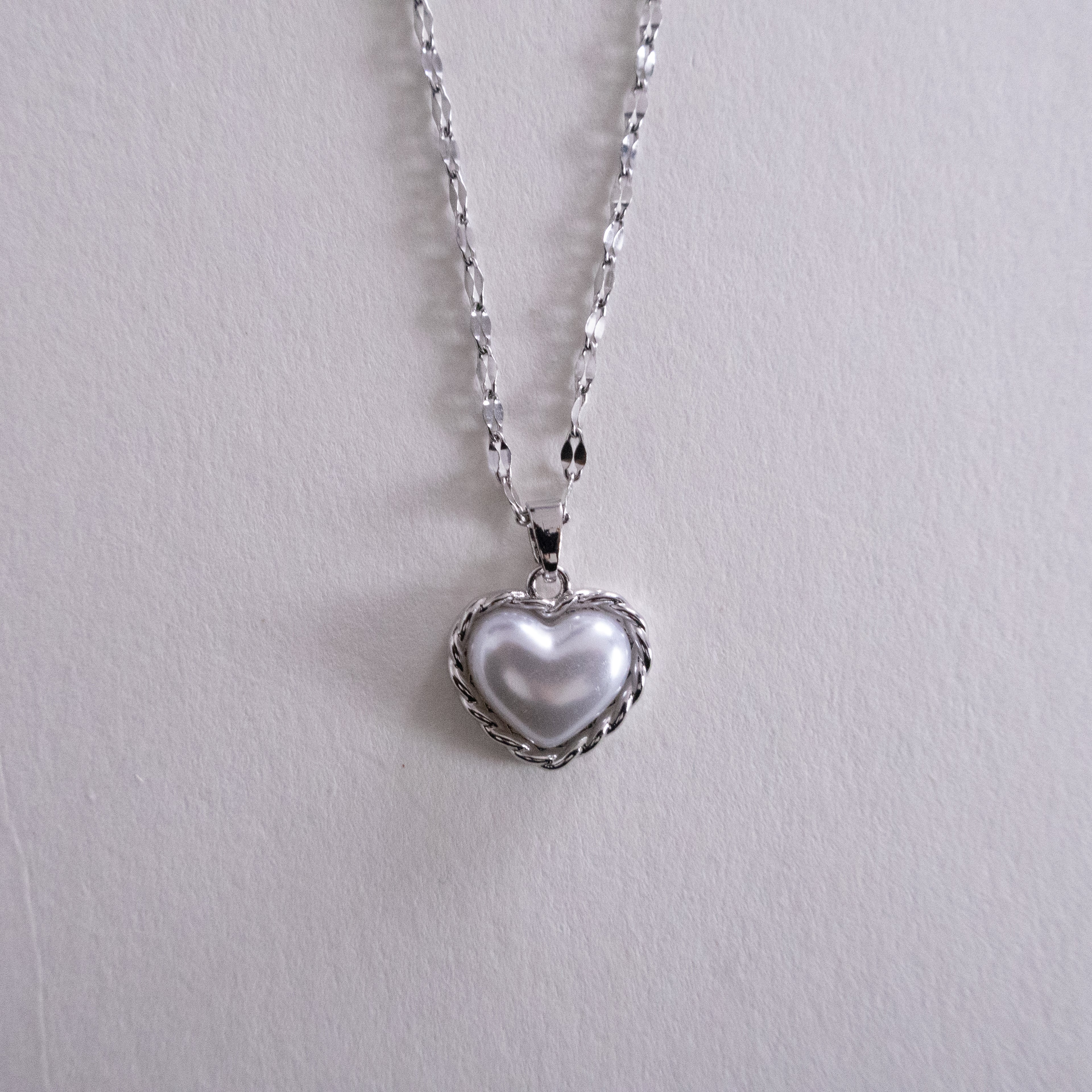 Close-up of a silver chain with black leather straps on a white background