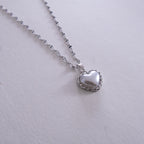 Silver heart-shaped pendant necklace on a light gray background