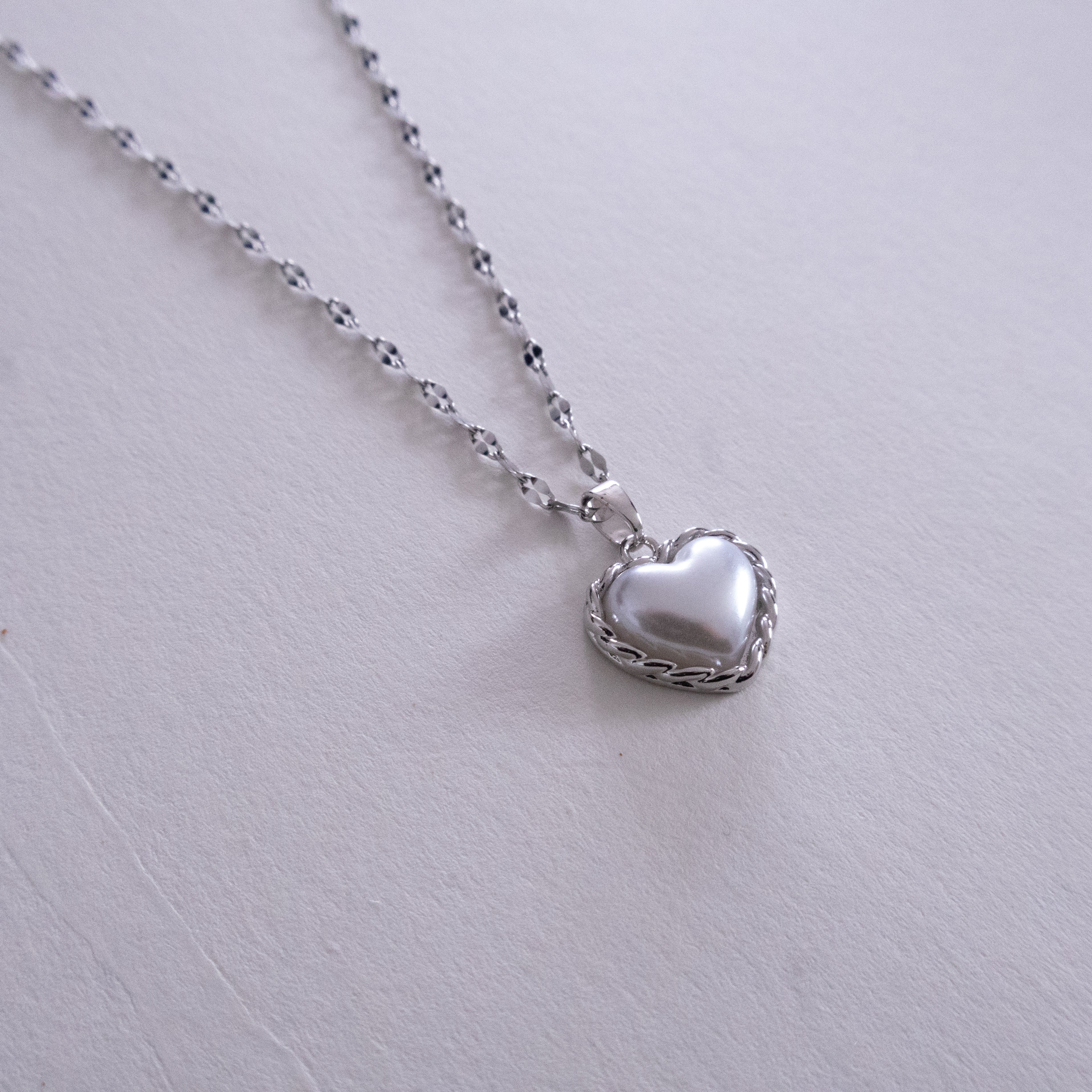 Silver heart-shaped pendant necklace on a light gray background
