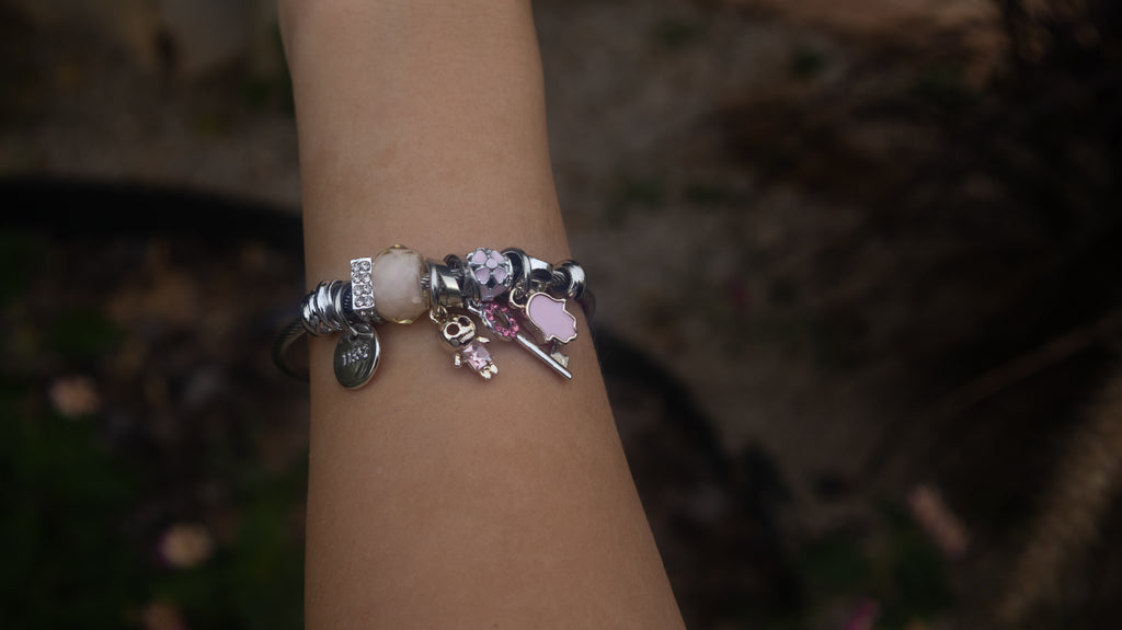 Bracelet with various charms on a blurred natural background