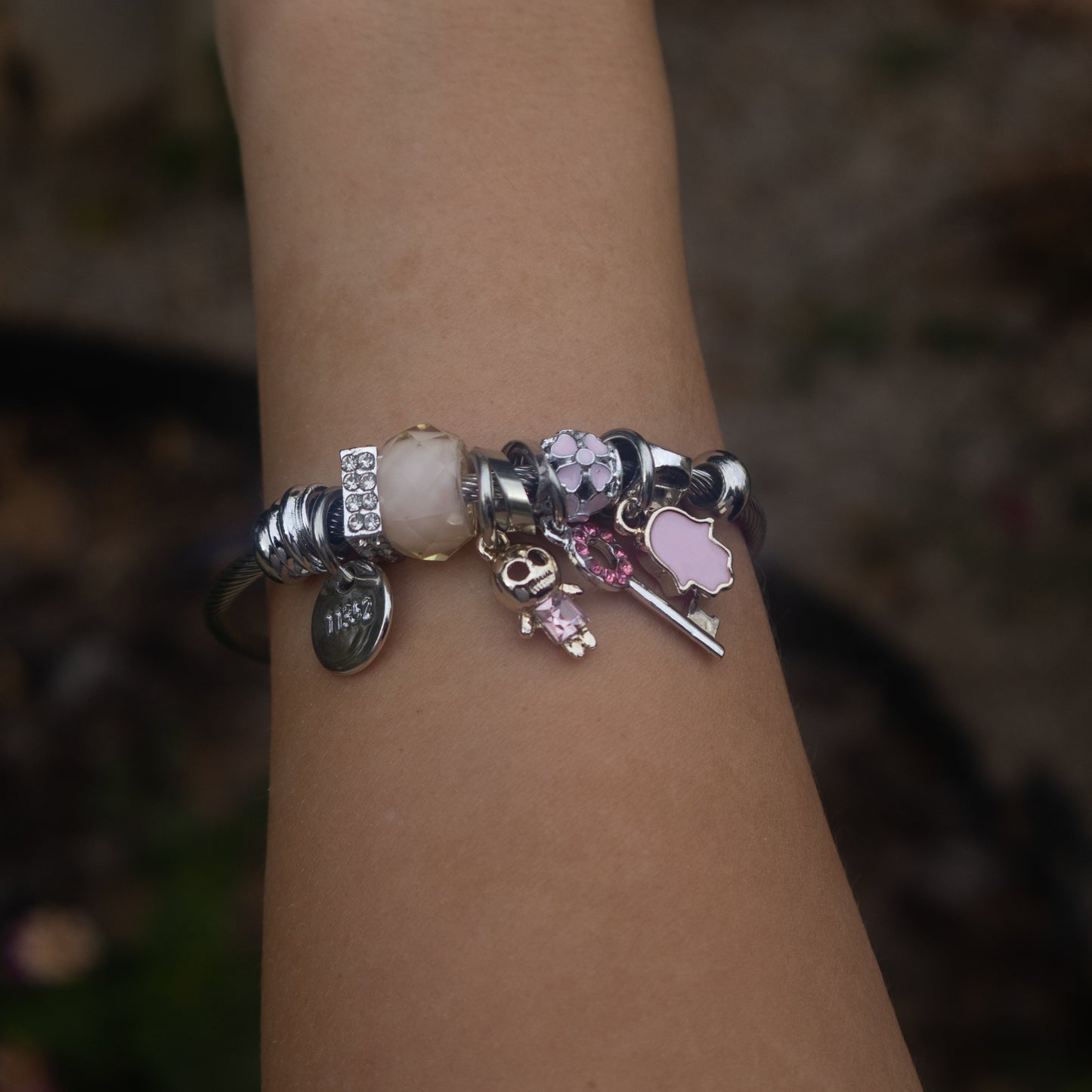 Bracelet with various charms on a blurred natural background