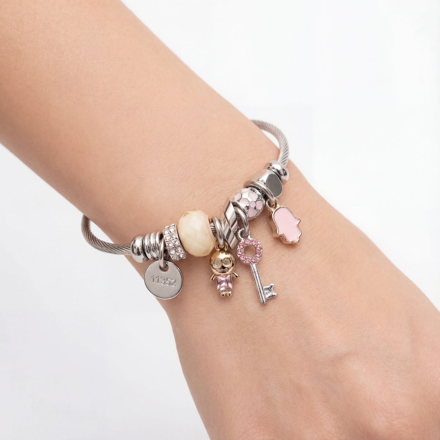 Bracelet with various charms on a wrist against a white background