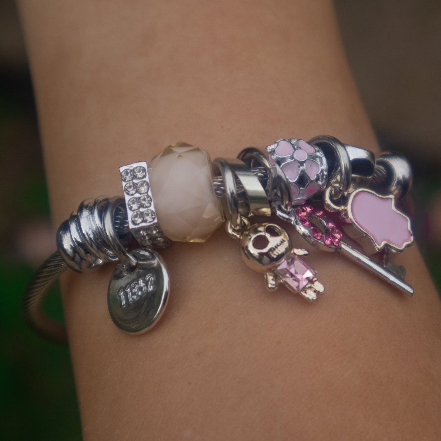 Close-up of a bracelet with various charms on a wrist against a blurred background