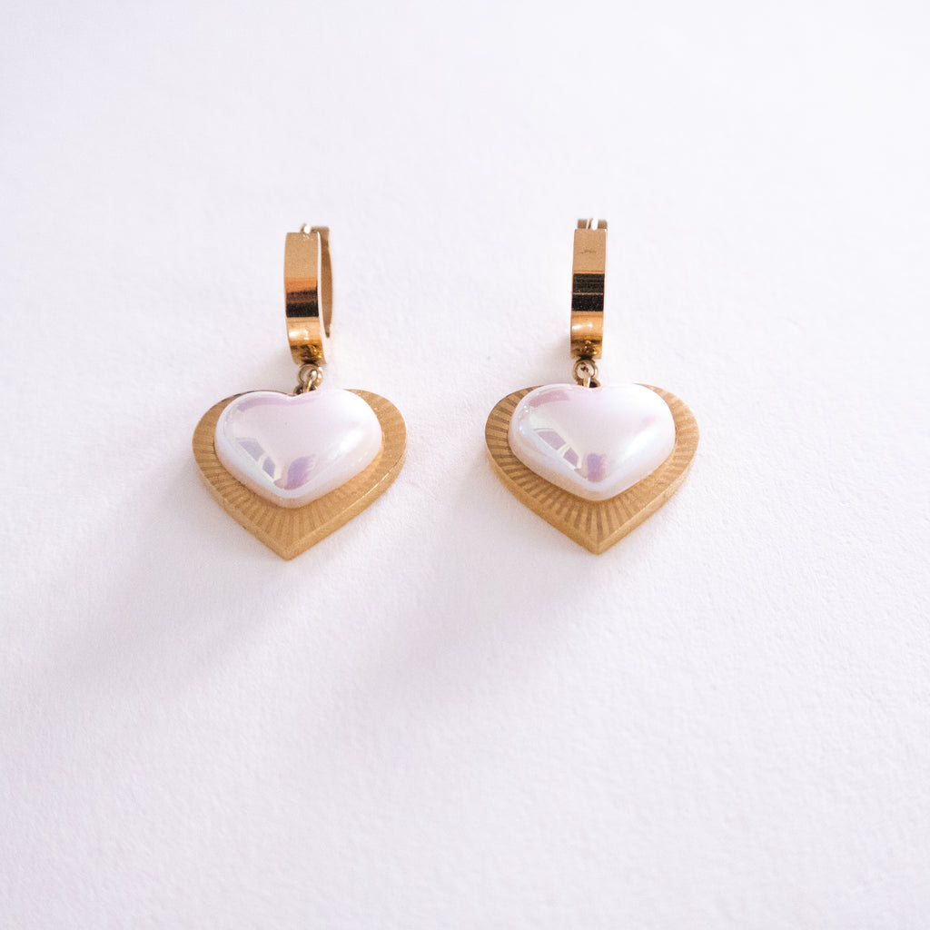 Heart-shaped earrings with gold and white design on a white background