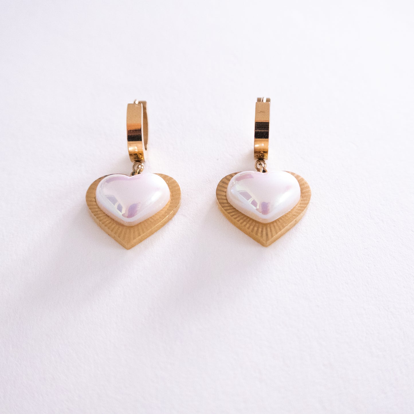 Heart-shaped earrings with gold and white design on a white background