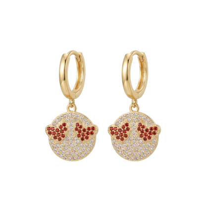 Gold hoop earrings with red and clear gemstone details on a white background