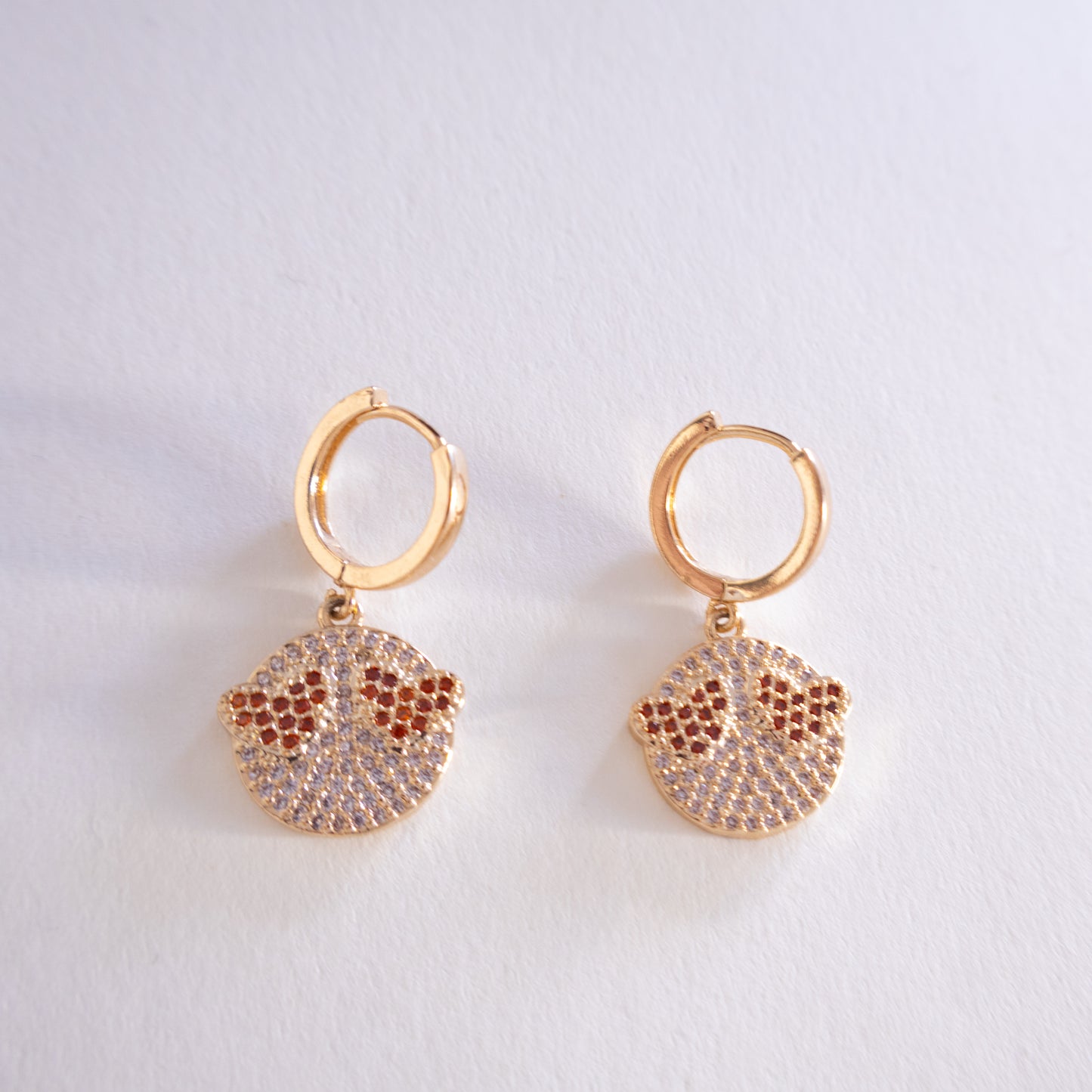 Pair of gold hoop earrings with round pave charms on a light gray background
