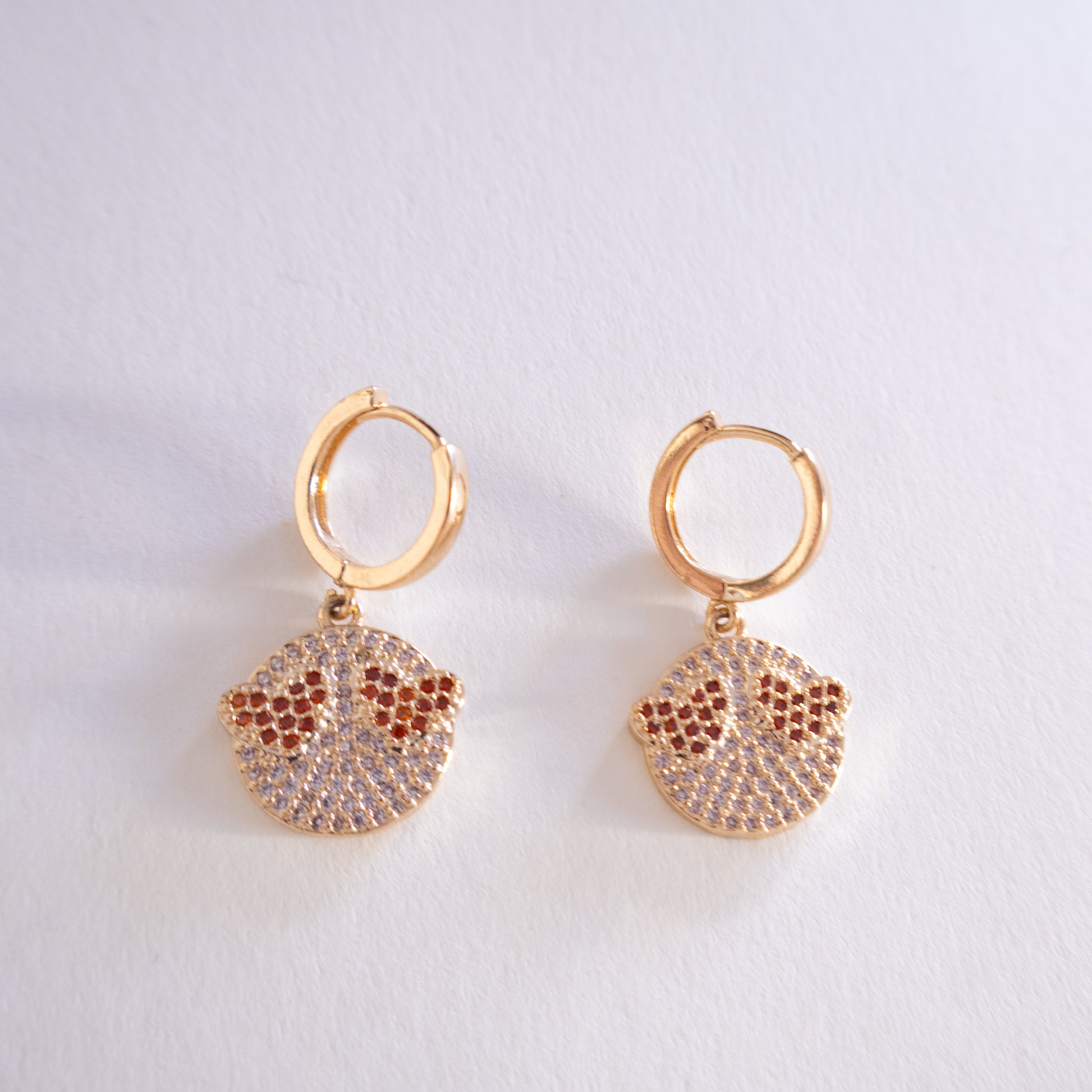 Pair of gold hoop earrings with round pave charms on a light gray background