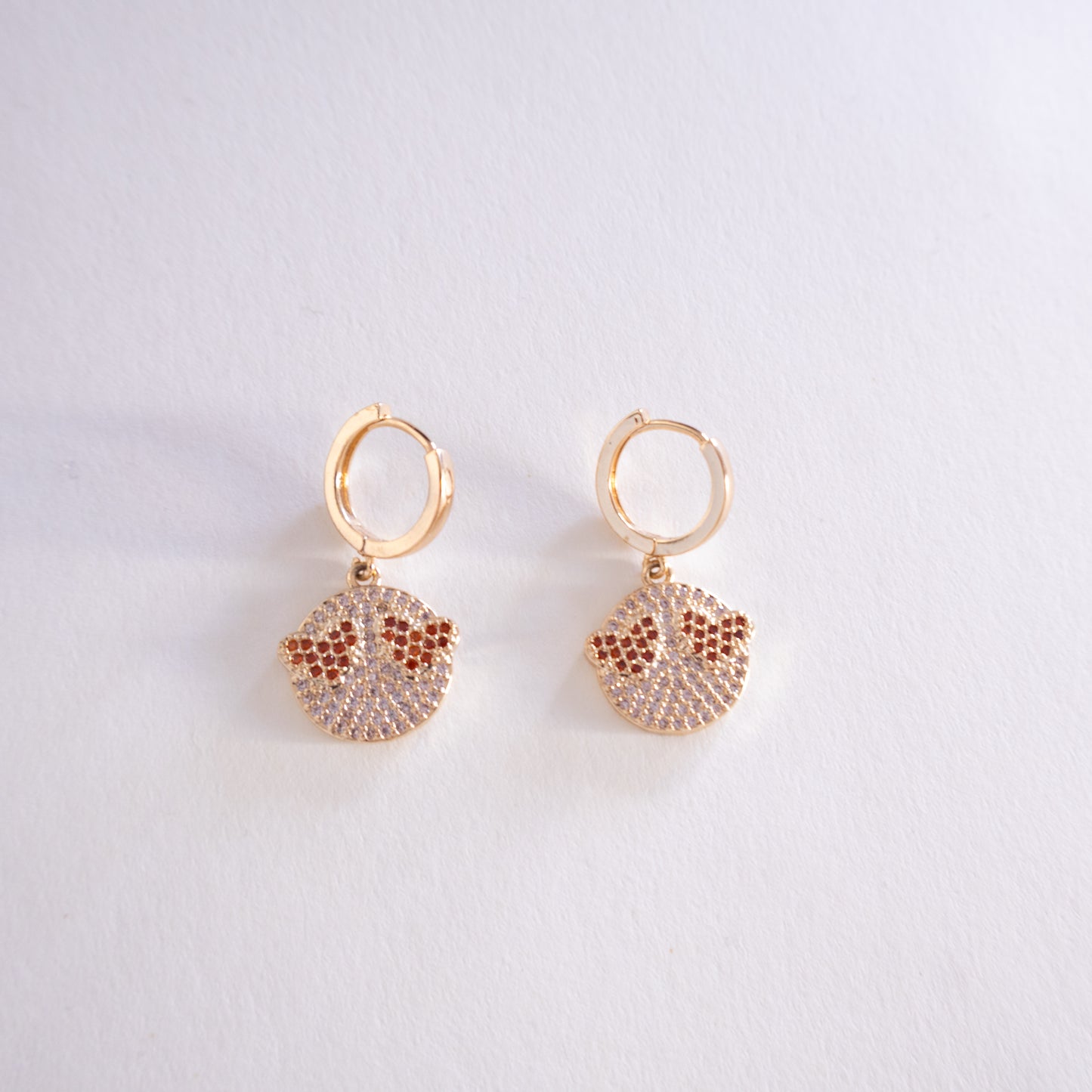 Gold hoop earrings with sand dollar designs on a light gray background