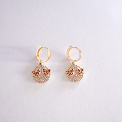Gold hoop earrings with sand dollar designs on a light gray background