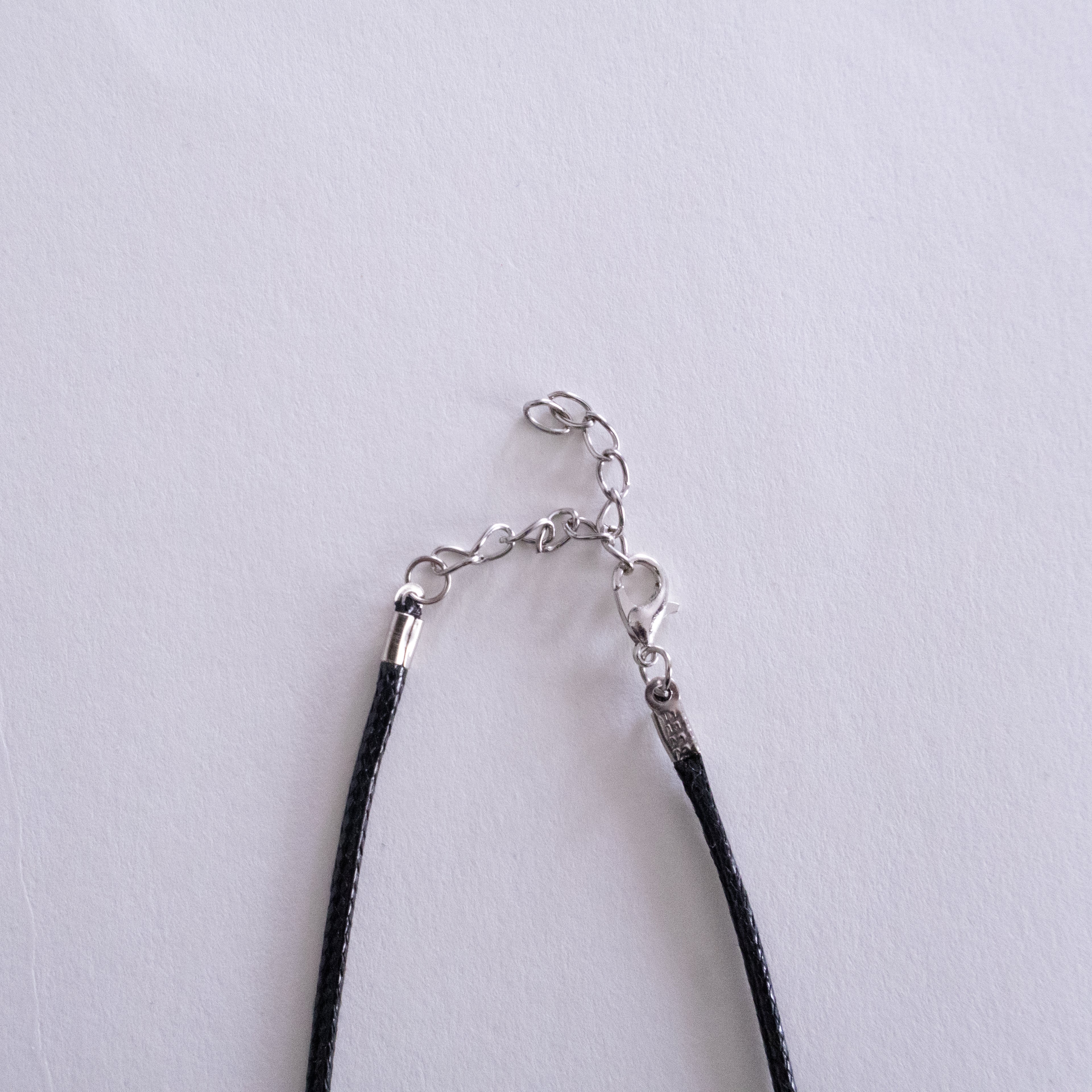 Necklace with black cord and silver clasp on a light gray background