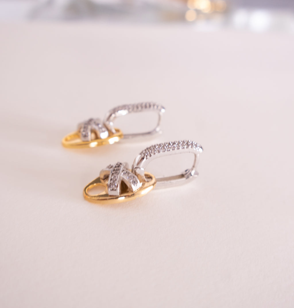 Pair of gold and silver earrings on a light background