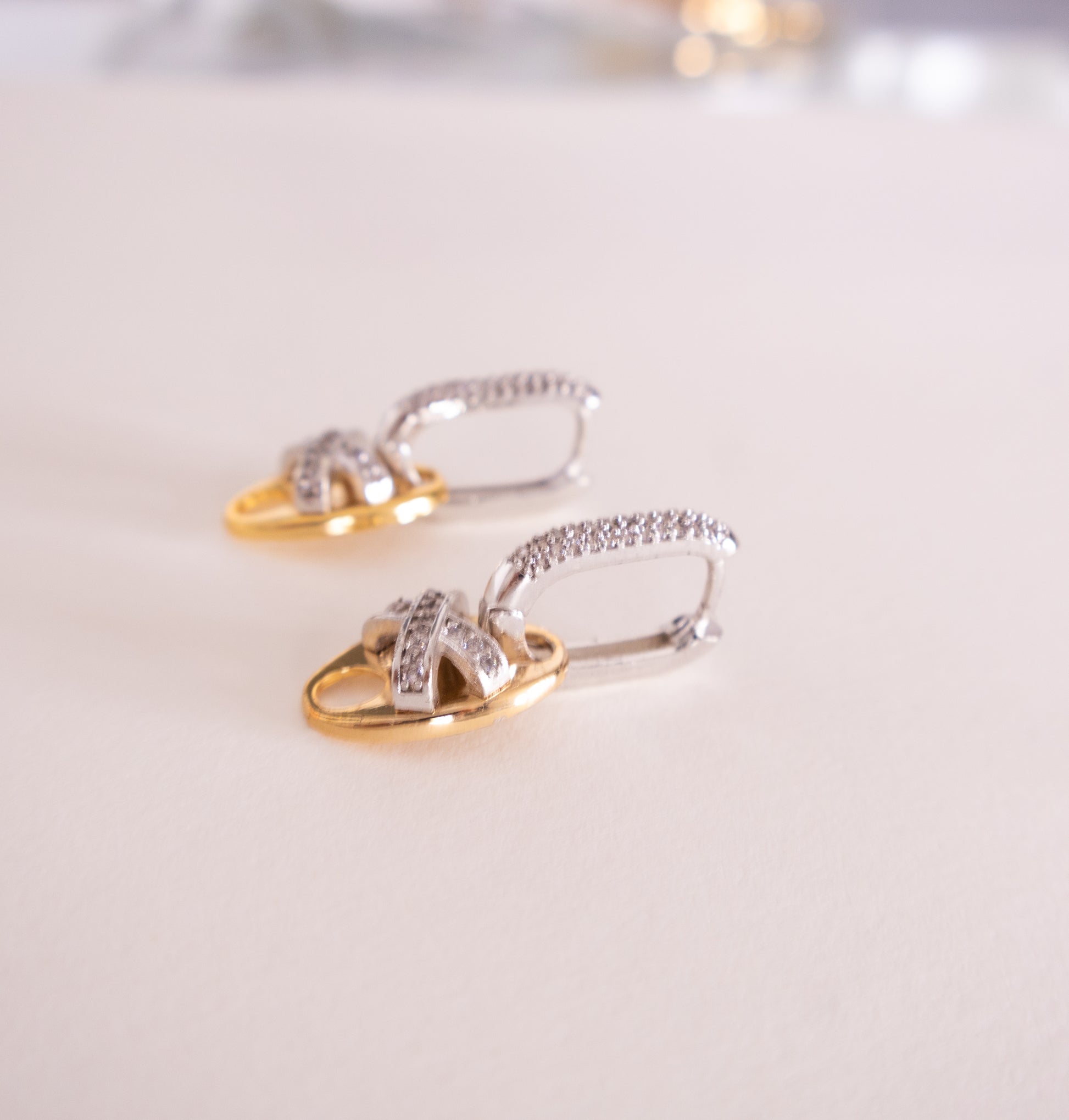 Pair of gold and silver earrings on a light background