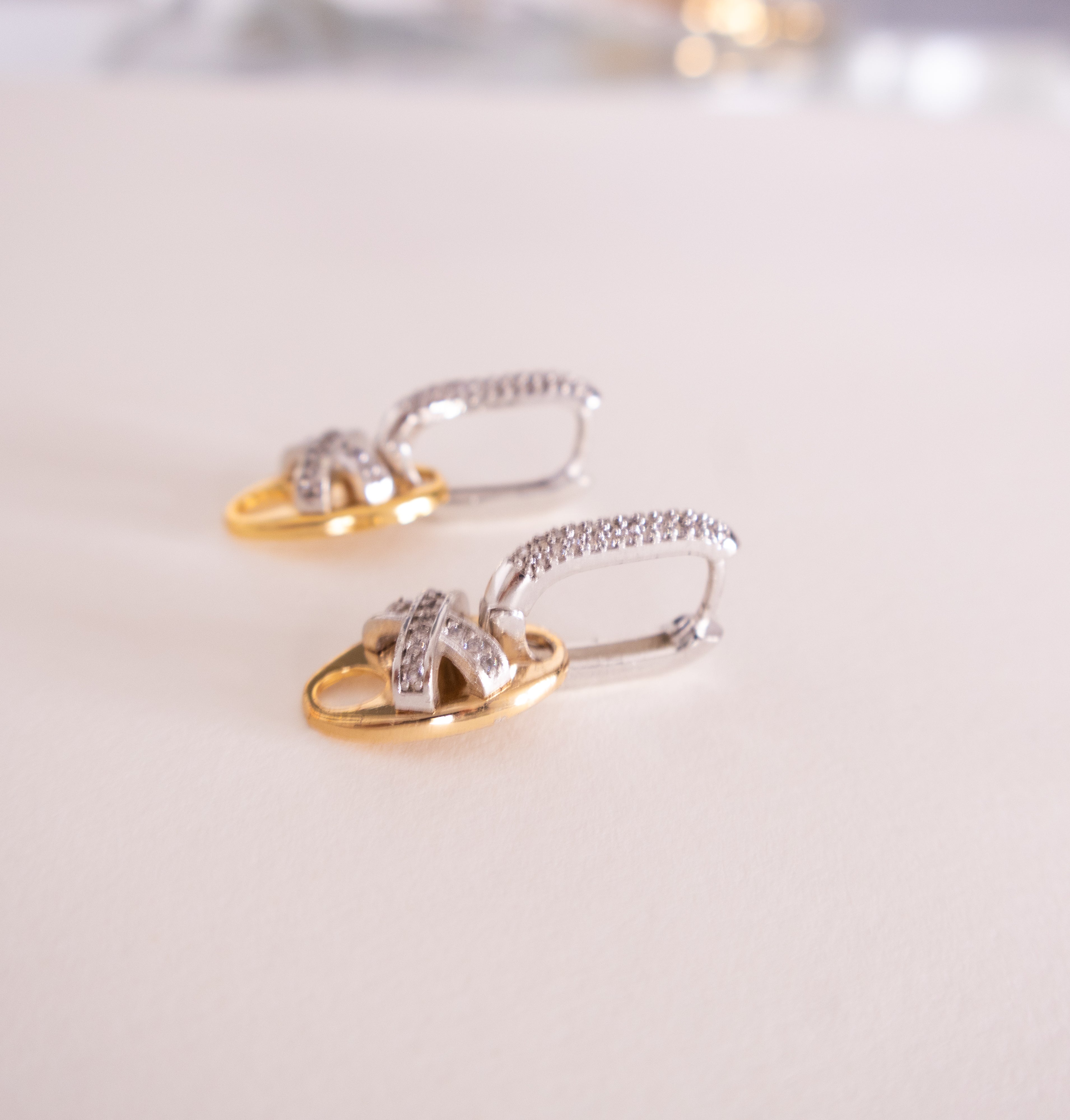 Pair of gold and silver earrings on a light background
