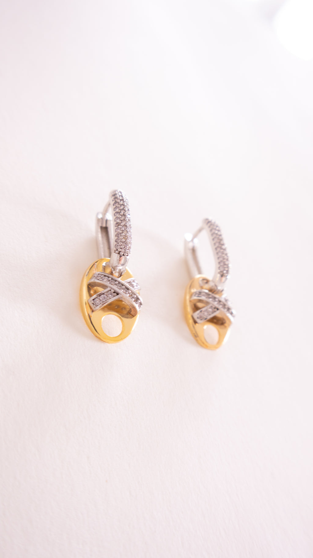 Pair of gold and silver earrings on a light pink background