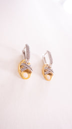 Pair of gold and silver earrings on a light pink background