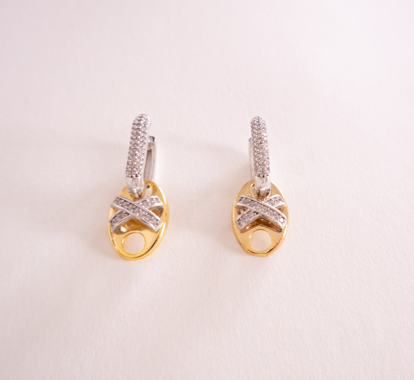 Pair of gold and silver earrings on a light pink background