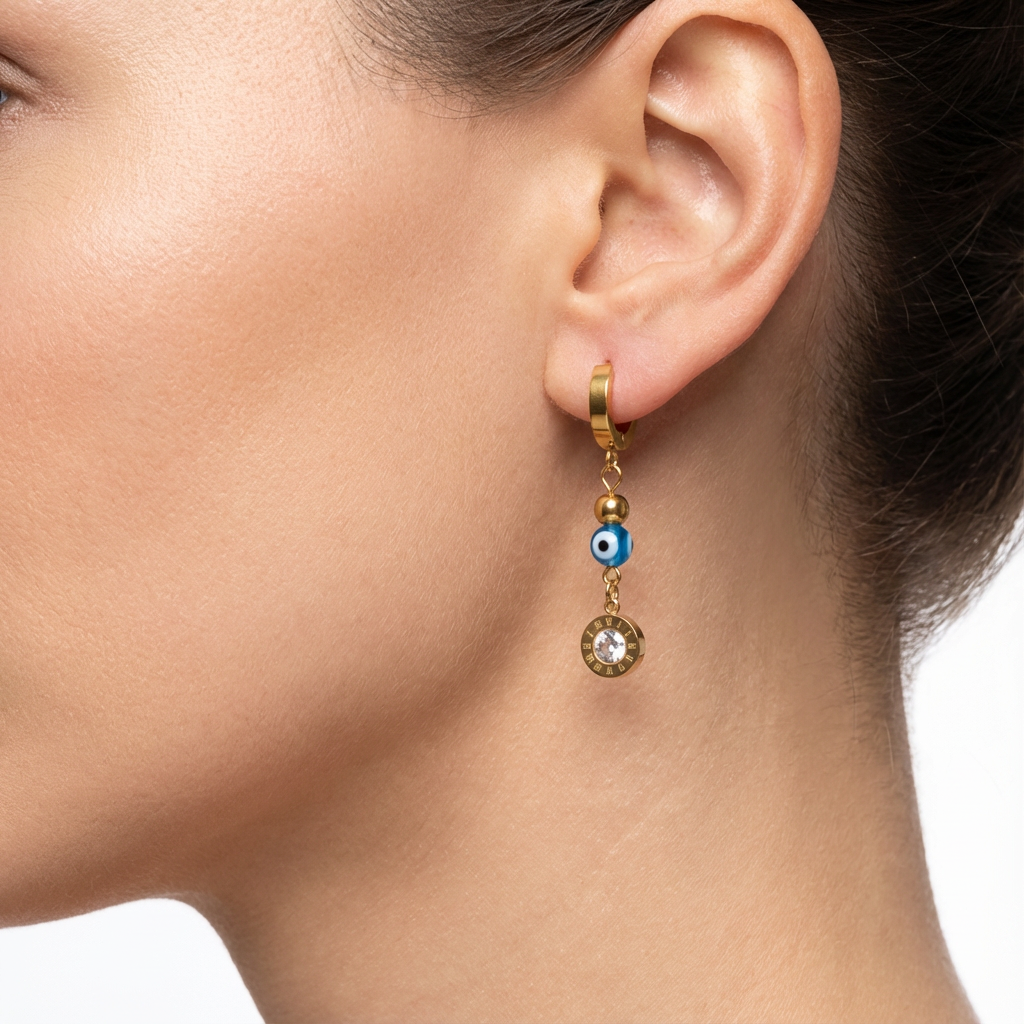 Close-up of an ear wearing a gold earring with a blue evil eye charm.