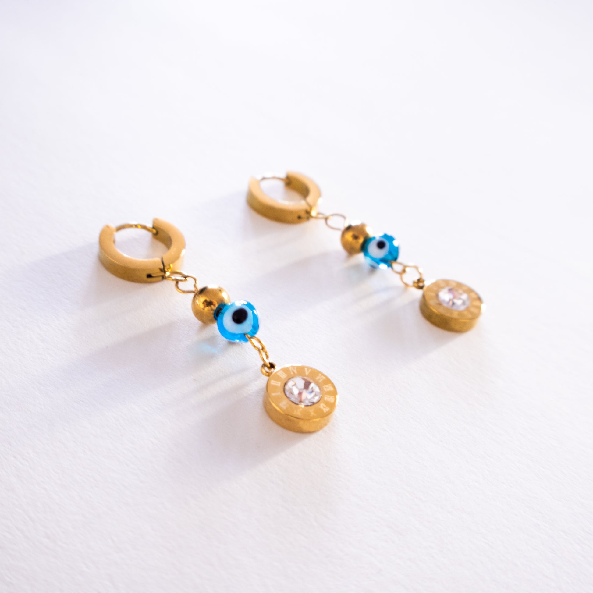 Gold hoop earrings with blue and clear bead charms on a white background