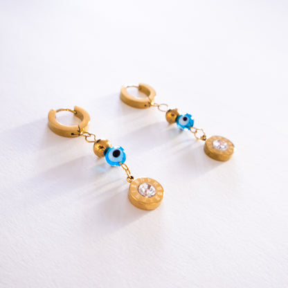 Gold hoop earrings with blue and clear bead charms on a white background