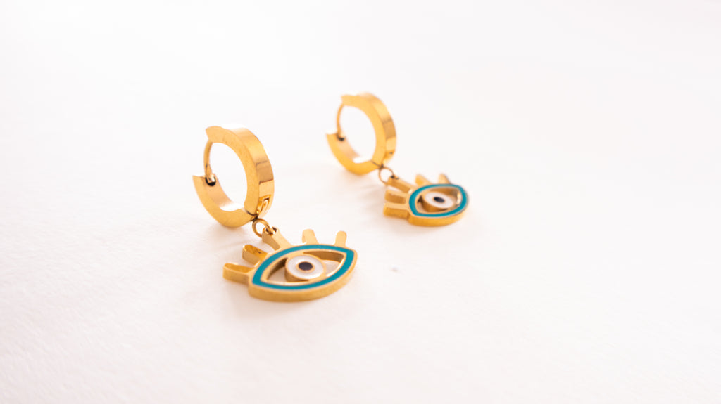 Gold hoop earrings with eye designs on a white background