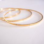 Three gold bangles on a white surface