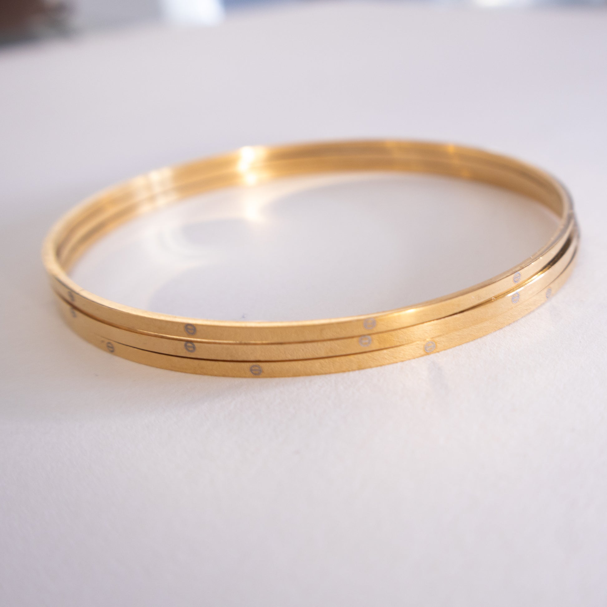 Gold bangles on a white surface