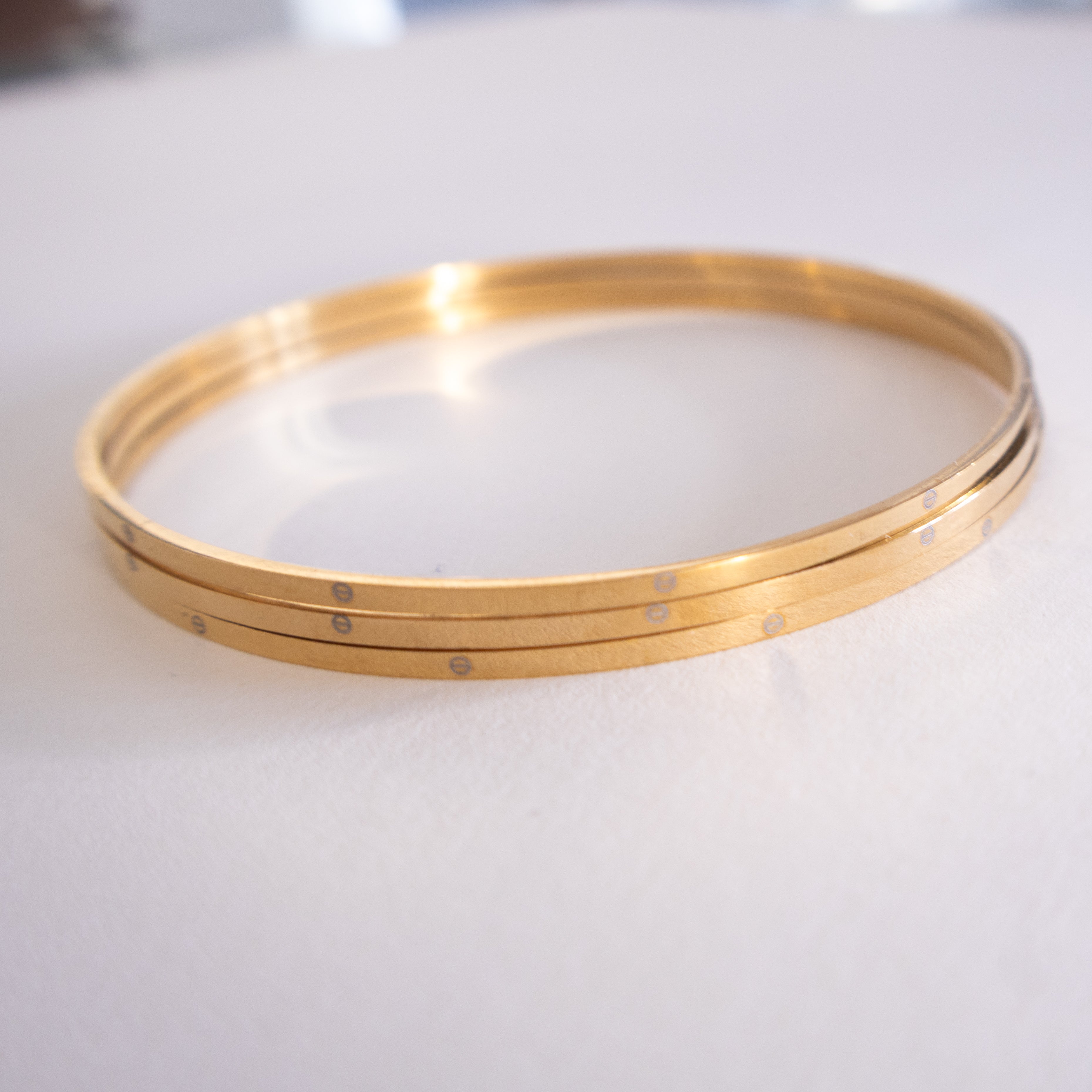 Gold bangles on a white surface